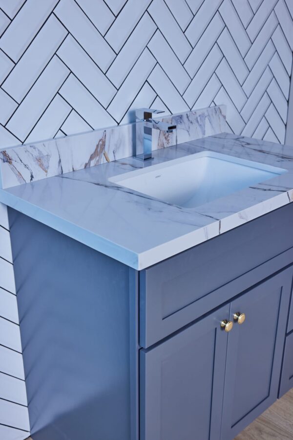 Modern bathroom sink with marble countertop and blue cabinet.