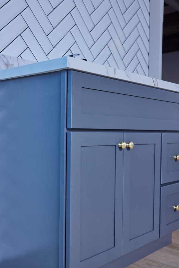 Blue kitchen cabinet with gold knobs and marble countertop.