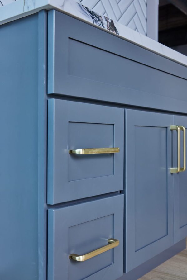 Blue kitchen cabinet with gold handles and marble countertop.