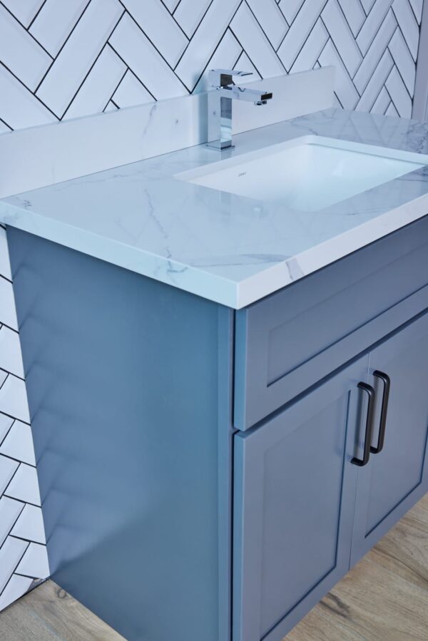 Blue bathroom vanity with marble countertop and modern handles.