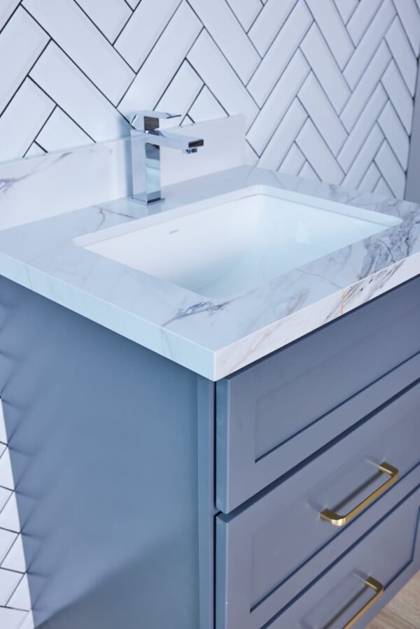 Modern bathroom vanity with marble countertop and herringbone tile backsplash.