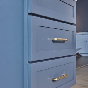 Blue kitchen cabinets with gold handles in modern design.