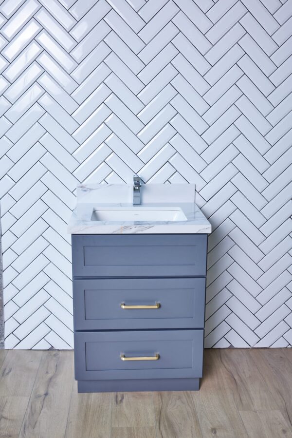 Gray bathroom vanity with herringbone tile backsplash.
