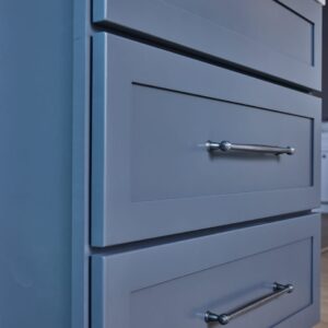 Blue kitchen cabinets with silver handles and marble countertop.