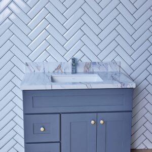 Gray bathroom vanity with marble countertop against herringbone tile wall.