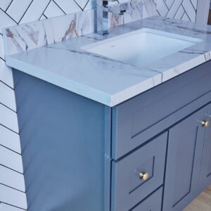 Blue bathroom vanity with marble countertop and herringbone tile backsplash.