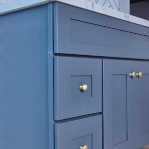 Blue kitchen cabinets with gold knobs and marble countertop.