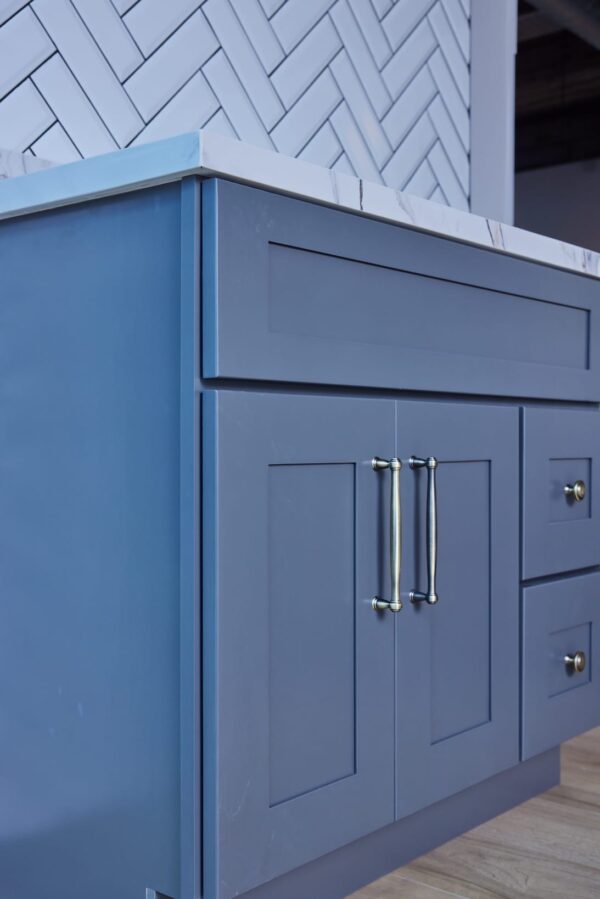 Blue kitchen cabinet with marble countertop and silver handles.