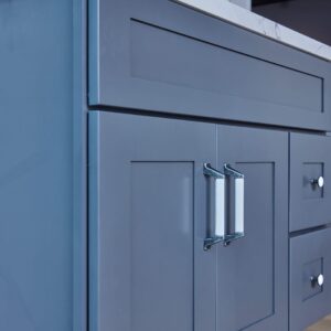 Blue kitchen cabinet with marble countertop and herringbone backsplash.