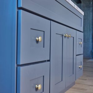 Blue kitchen cabinets with gold handles on wooden floor.