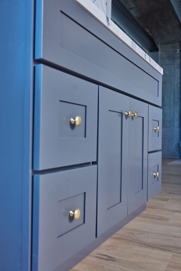 Blue kitchen cabinets with gold handles on wooden floor.