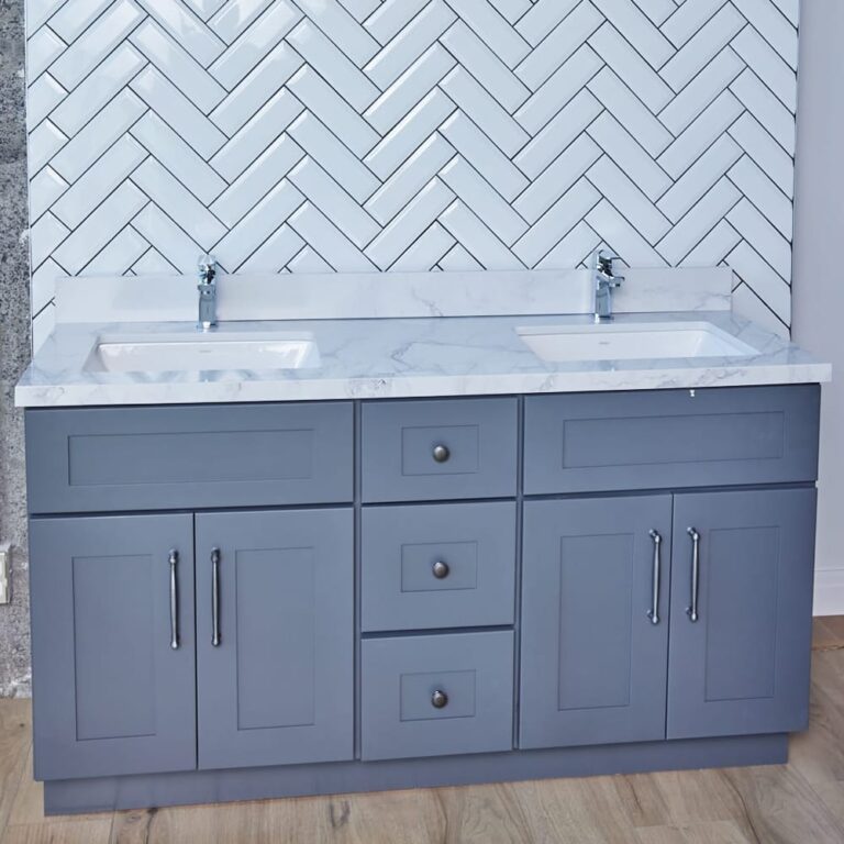 Gray double-sink bathroom vanity with marble countertop and herringbone tile backsplash.