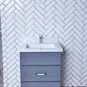 Gray bathroom vanity against white herringbone tile wall.