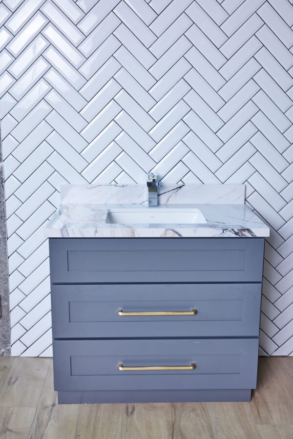 WSDG-3VDB3620-32.5.jpg Gray bathroom vanity with marble countertop and herringbone tile backsplash.