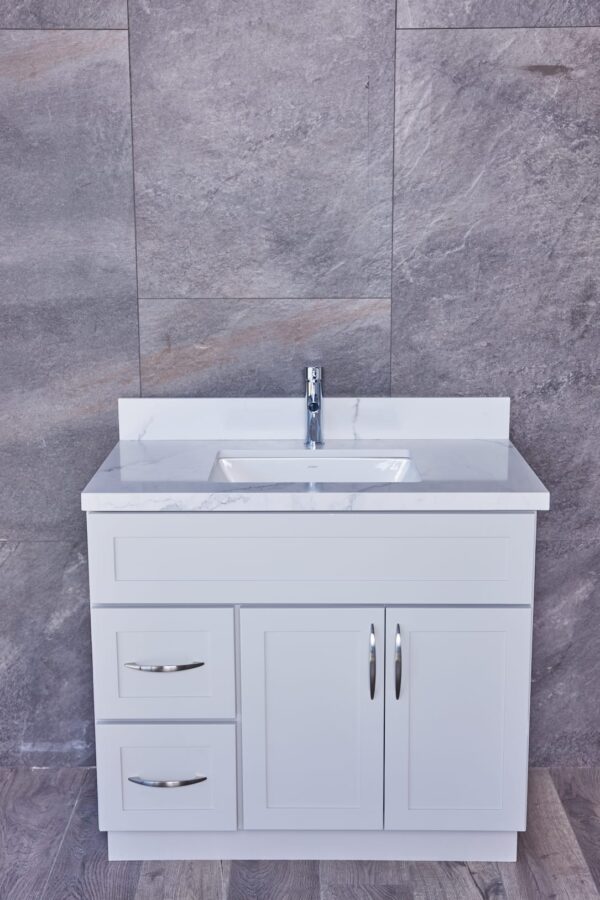 White bathroom vanity with marble countertop and modern faucet.