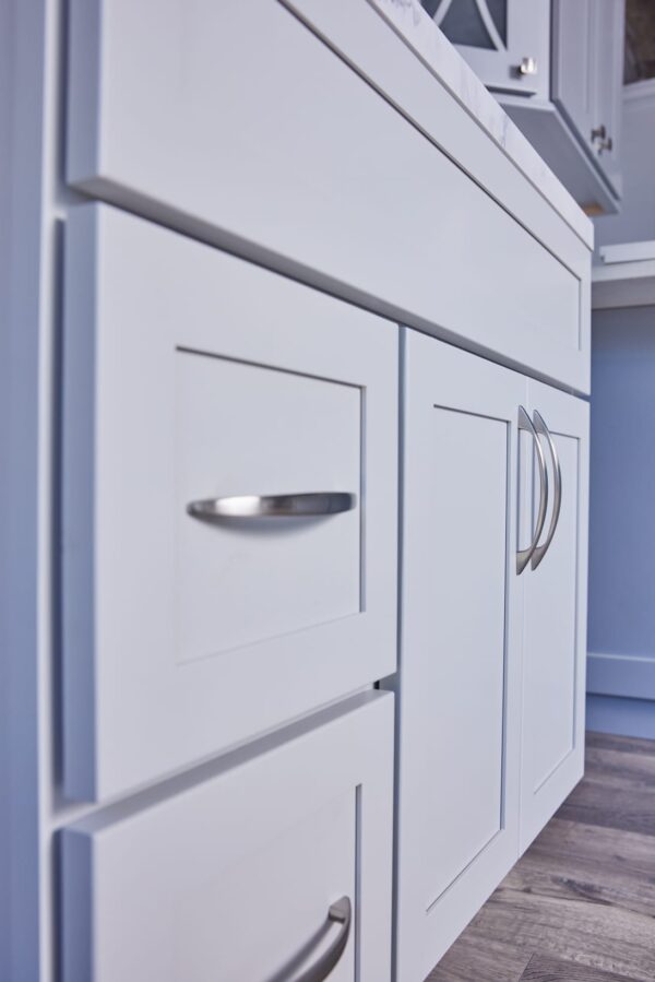 White kitchen cabinets with silver handles, close-up view.