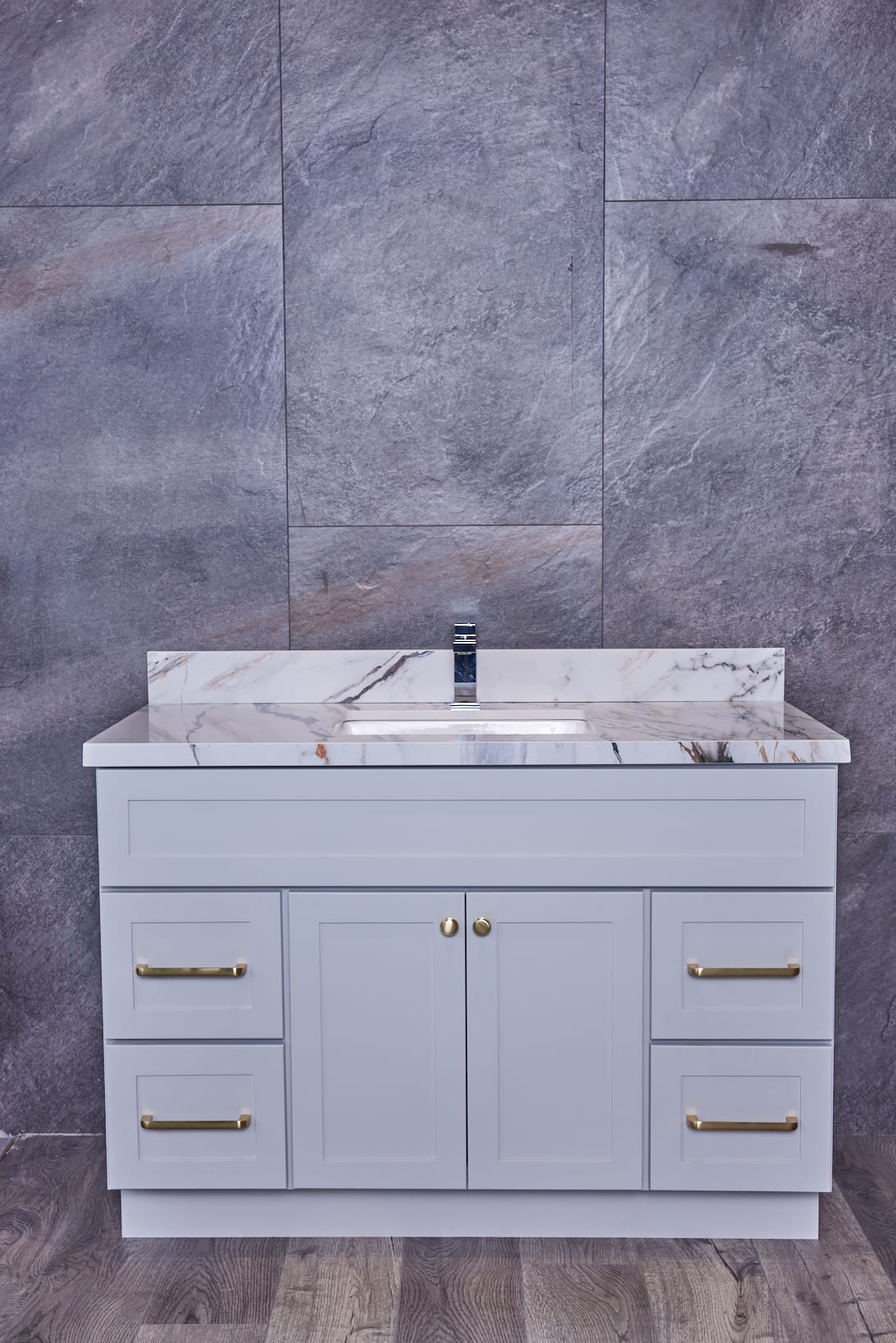 Modern bathroom vanity with marble countertop and gray cabinets.
