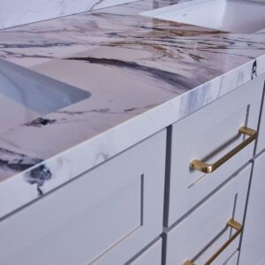 Marble countertop with gold handles on white cabinets.