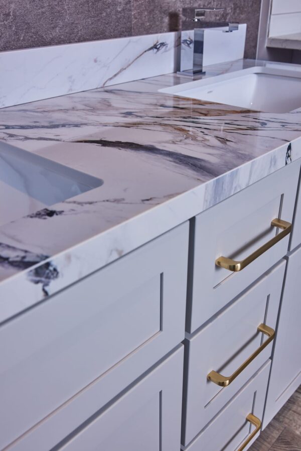 Marble countertop with gold handles on white cabinets.