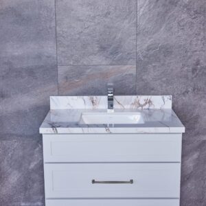 White bathroom vanity with marble countertop against gray tiled wall.