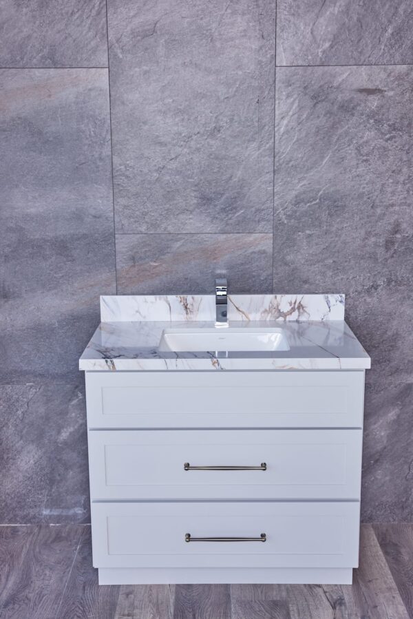 White bathroom vanity with marble countertop against gray tiled wall.