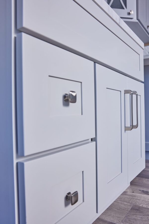 White kitchen cabinets with modern handles in a blue-themed kitchen.
