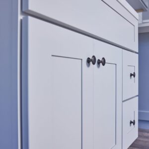 White kitchen cabinet with black knobs and drawers.