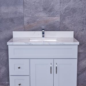 White bathroom vanity with marble countertop against gray stone wall.
