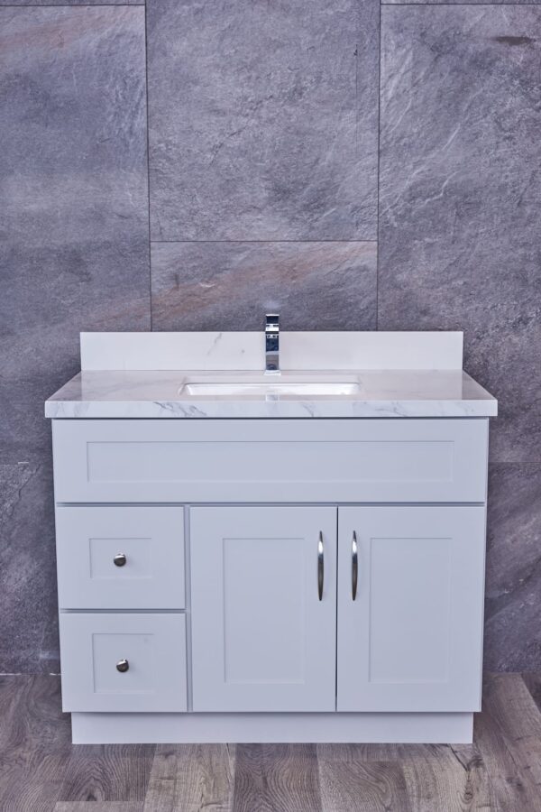 White bathroom vanity with marble countertop against gray stone wall.