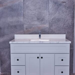 White bathroom vanity with marble countertop and gray tile background.