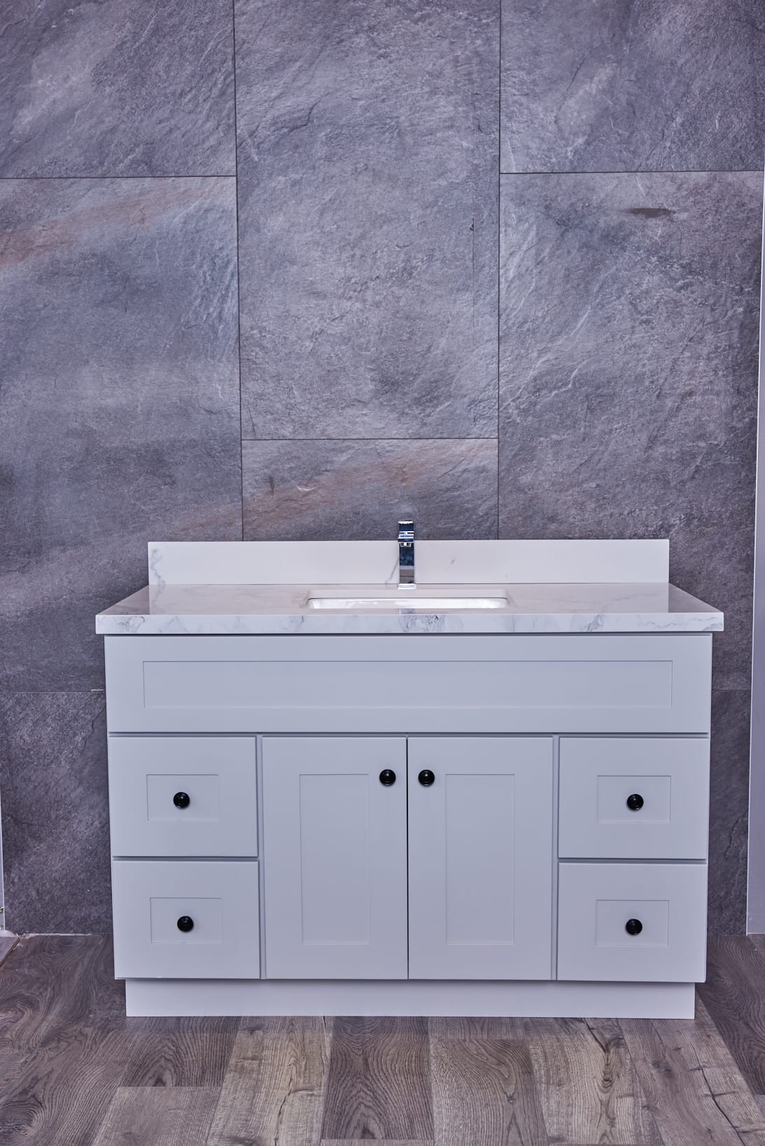 White bathroom vanity with marble countertop and gray tile background.