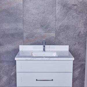 White bathroom vanity with marble countertop against gray tiled wall.