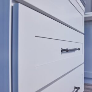 White kitchen cabinet with sleek black handle.