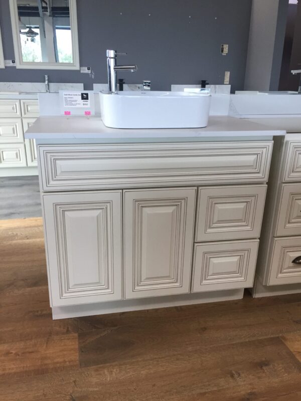 White bathroom vanity with sink on wooden floor.