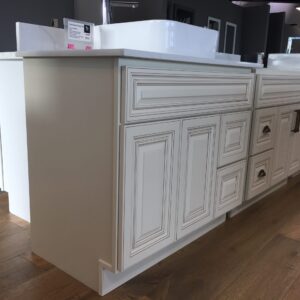 Cream kitchen cabinets with detailed paneling and a white countertop.