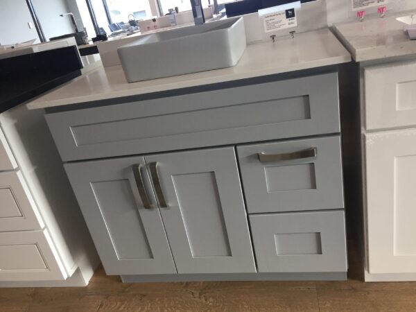 Gray kitchen cabinet with sink on display in showroom.