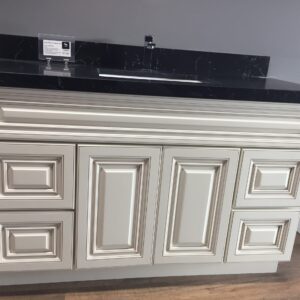White kitchen cabinet with black countertop and sink.