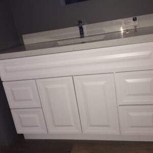 White bathroom vanity with multiple drawers and a countertop sink.