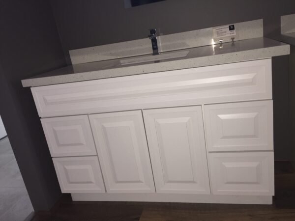 White bathroom vanity with multiple drawers and a countertop sink.