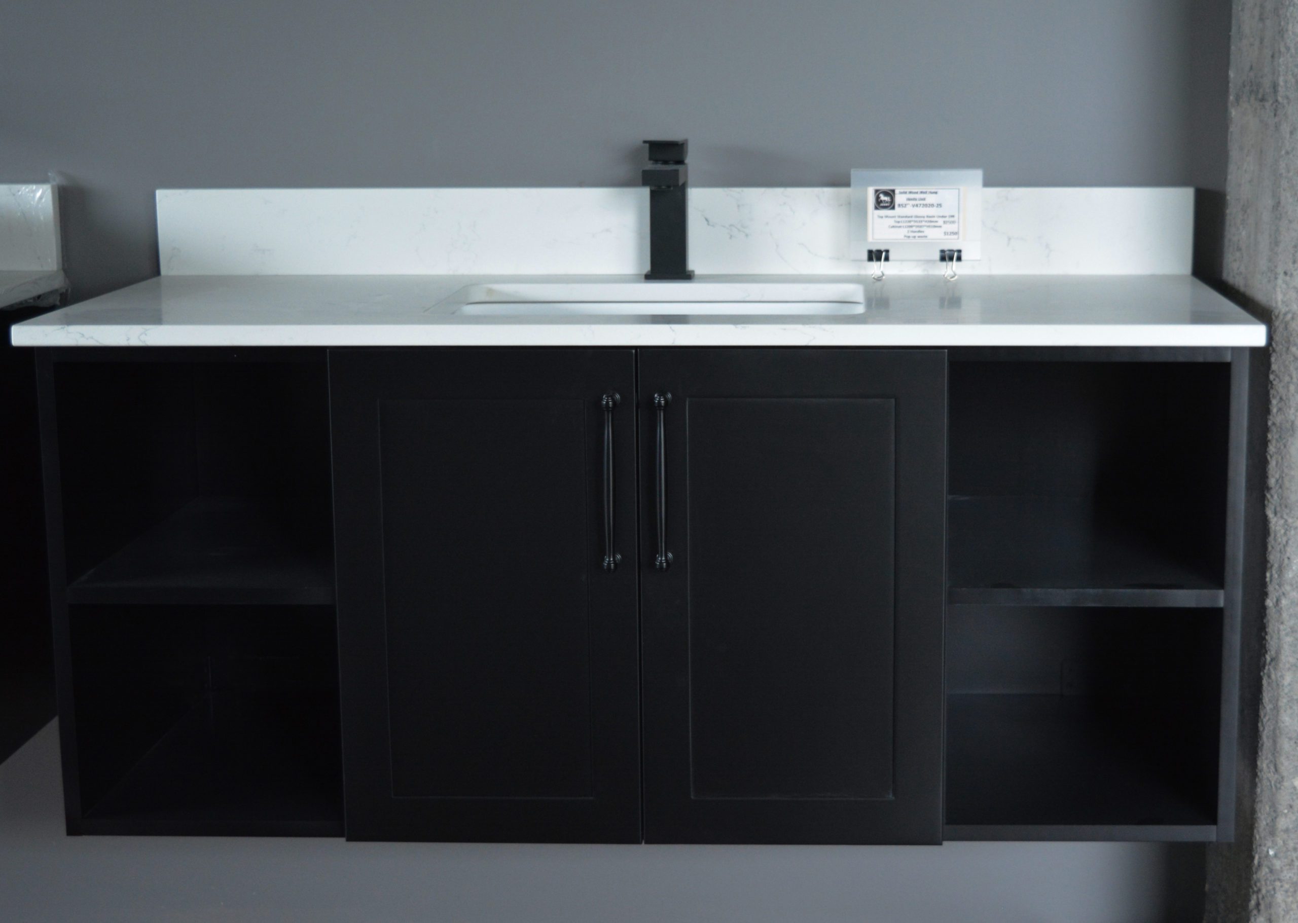 Black kitchen cabinet with white countertop and modern faucet.