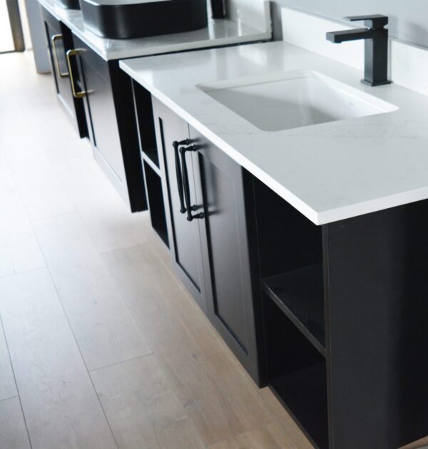 Modern kitchen with black cabinets and white countertops.