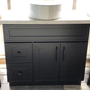 Black kitchen cabinet with drawers and a white countertop.