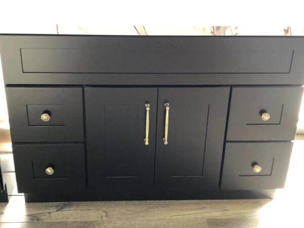Black kitchen cabinet with silver handles on a wooden floor.
