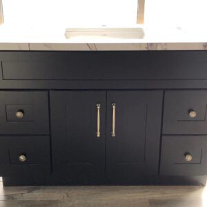 Black kitchen cabinet with marble countertop and brass handles.