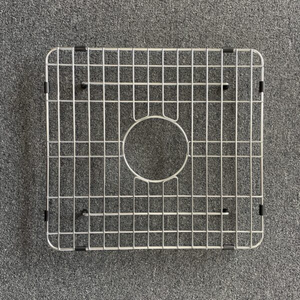 Square metal sink grid on a gray carpet background.