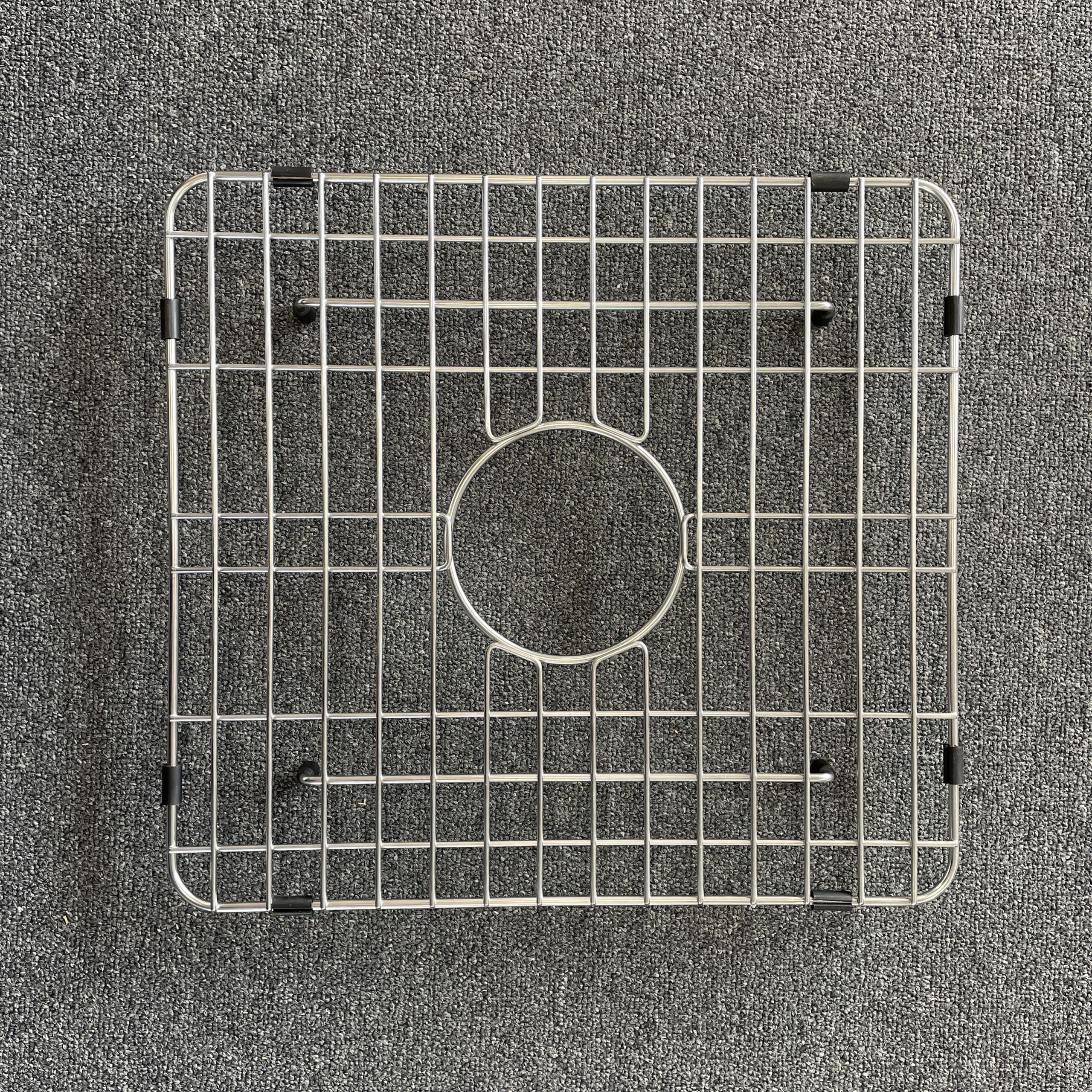 Square metal sink grid on a gray carpet background.