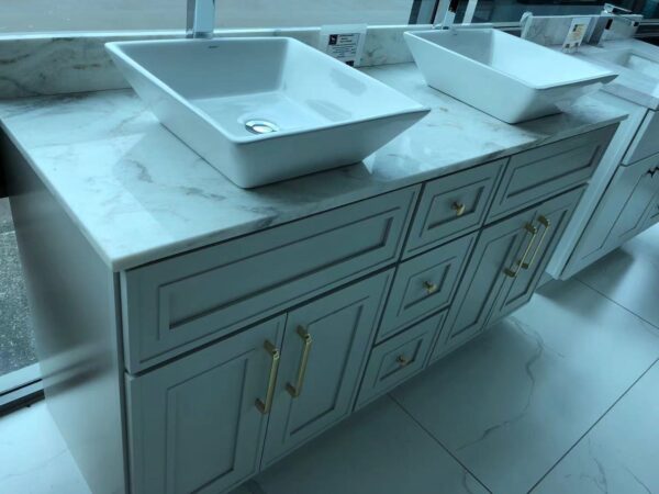 Light grey kitchen cabinet with marble countertop and two sinks.