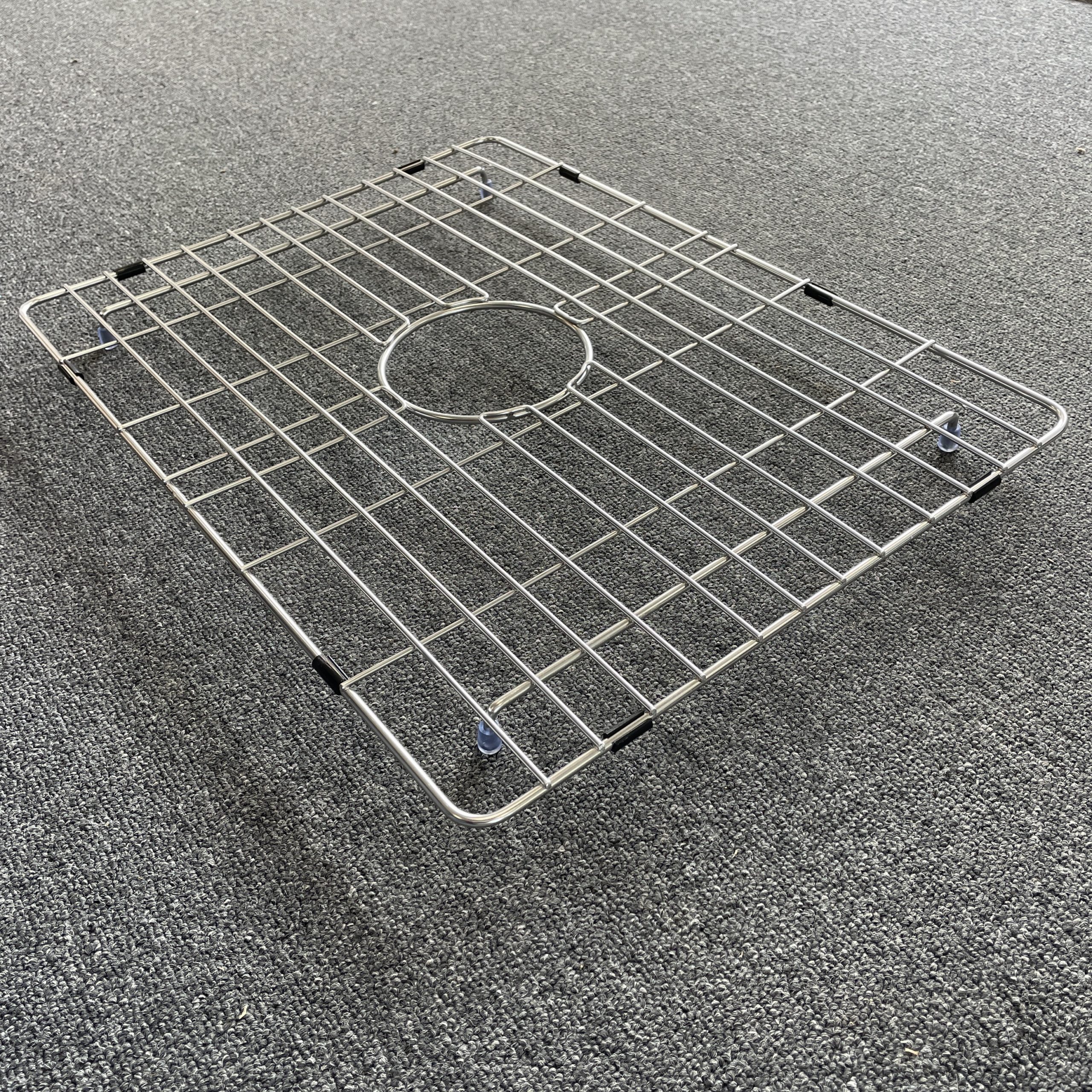 Stainless steel sink grid on gray carpet.