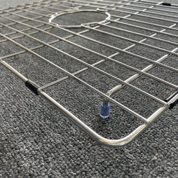 Stainless steel sink grid on textured carpet.