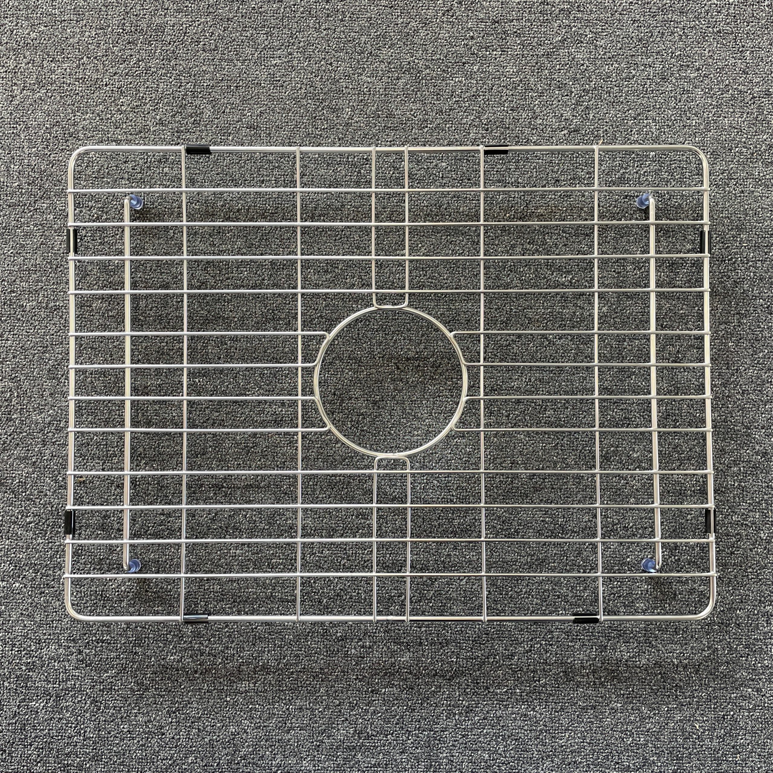 Stainless steel sink grid on a textured surface.